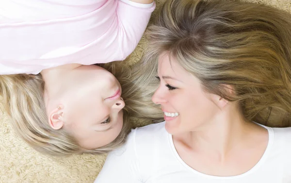 Petite fille et sa mère couchés ensemble à l'intérieur . — Photo