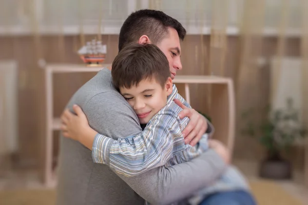 Sad son hugging his dad indoor — Stock Photo, Image