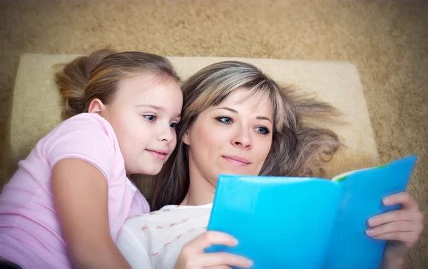 Jeune mère lit un livre à sa fille . — Photo