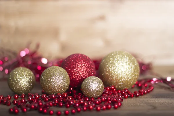 Bolas de Natal de ouro e cor vermelha em um fundo de madeira — Fotografia de Stock