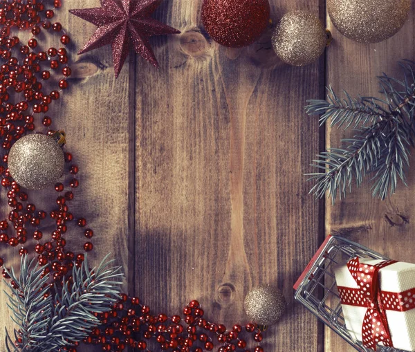 Cornice con palline di Natale, regalo e cesto della spesa su sfondo di legno — Foto Stock