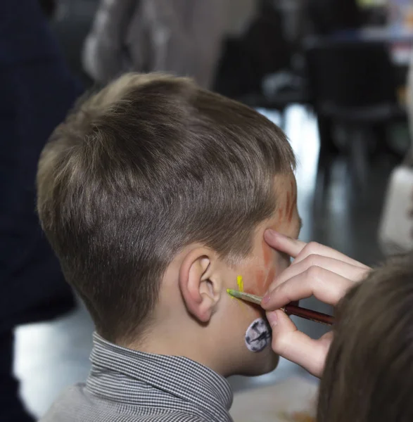 Kinderanimator - artist's hand trekt schminken naar jongetje — Stockfoto