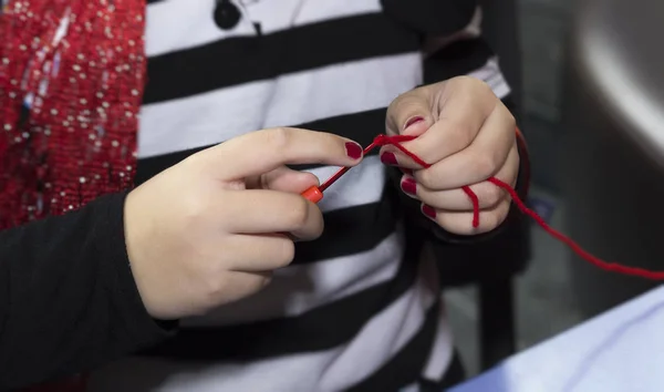 Fille mains tricot avec crochet et fil rouge — Photo