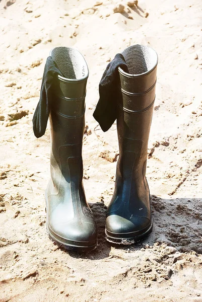 Green rubber boots with sweaty stockings on sand background — Stock Photo, Image