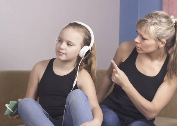 Красивая женщина ругает свою дочь-подростка, девушка слушает музыку в наушниках и игнорирует свою маму — стоковое фото