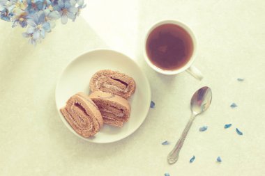 Lezzetli breakfast - bisküvi ile çay güneşli Menekşe bir arka plan üzerinde rulo