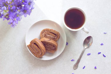 Lezzetli breakfast - bisküvi ile çay güneşli Menekşe bir arka plan üzerinde rulo