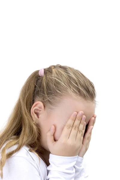 Una niña cubriéndose la cara con las manos. La niña rubia se cubre la cara con las manos aisladas. Chica ocultar la cara bajo las manos, jugando al escondite . —  Fotos de Stock