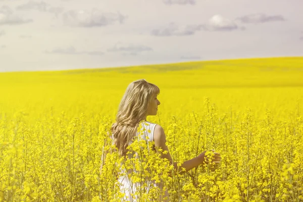 Женщина с длинными волосами вид сзади, желтое рапсовое поле канолы наслаждаясь природой и солнечным светом . — стоковое фото