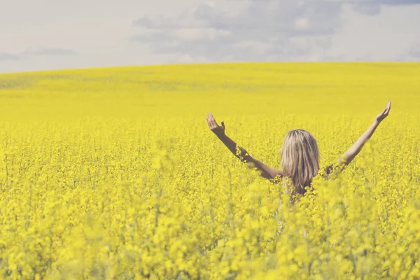 Mulher com cabelos longos em pé no prado de colza amarelo com as mãos levantadas. Conceito de liberdade e felicidade . — Fotografia de Stock