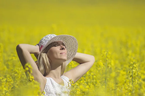 Jovem com um chapéu desfrutando de verão no campo de estupro . — Fotografia de Stock