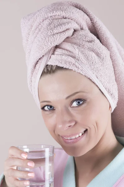 Jeune femme en robe tenant un verre d'eau, regardant la caméra et souriant — Photo