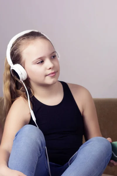 Joven adolescente escucha música desde el teléfono en los auriculares en casa . — Foto de Stock