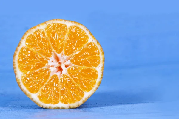 Свіжі напіврізані апельсини на синьому дерев'яному столі . — стокове фото
