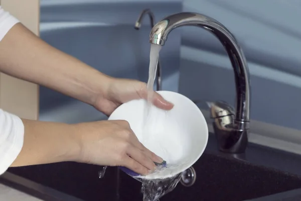 Mujer manos lavando platos bajo el agua corriente en el fregadero . — Foto de Stock