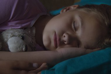 Küçük sarışın çocuk oyuncak ile onun yatakta uyuyor.