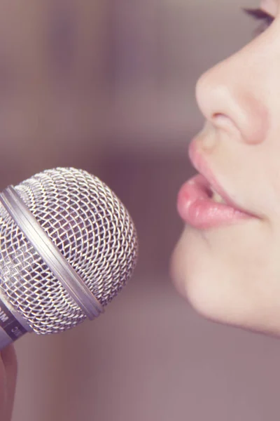 Крупный план пения кавказской девочки. Девушка эмоционально поет в микрофон, держа его за руку. . — стоковое фото