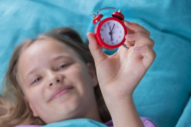 güzel küçük bir kız ile çalar saat yatak yatak odasında.