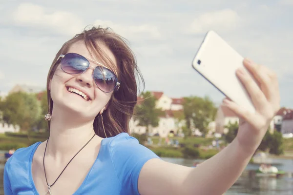 美しい女性、instagram。日当たりの良い夏の日に市内の屋外スマート フォンと selfie を取る女性。クローズ アップ ショット. — ストック写真