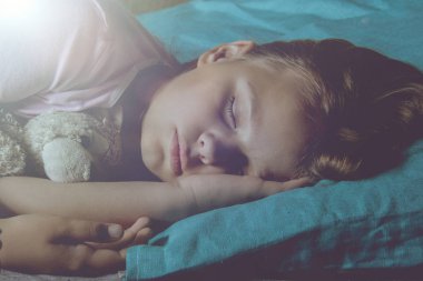 Küçük sarışın çocuk oyuncak ile onun yatakta uyuyor.
