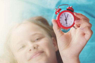 güzel küçük bir kız ile çalar saat yatak yatak odasında.