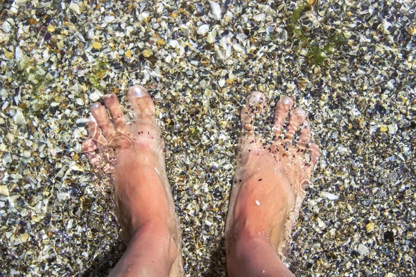 Žena je bosé nohy, pokryté pískem na pláži. — Stock fotografie