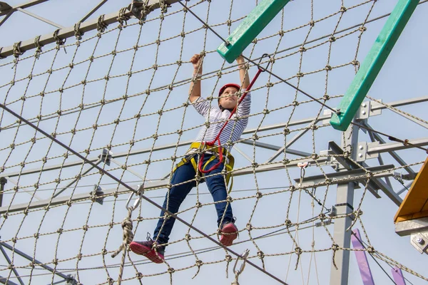 Menina escalando em um curso de cordas ao ar livre . — Fotografia de Stock