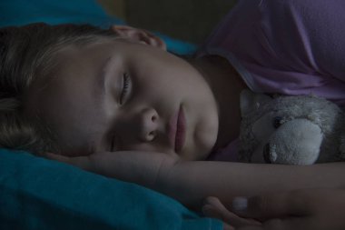 Küçük sarışın çocuk oyuncak ile onun yatakta uyuyor.