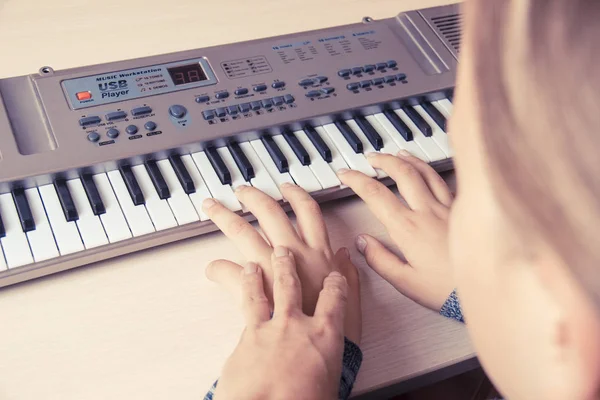 Женщина учит маленькую девочку играть на синтезаторе . — стоковое фото