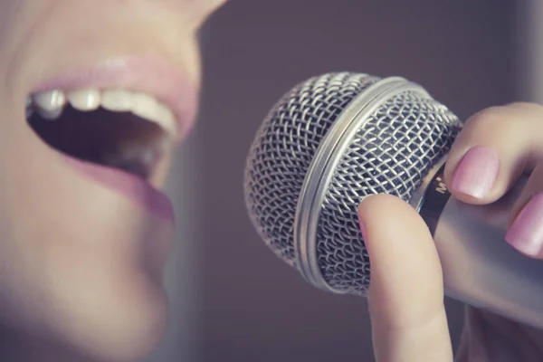Женщина поет в микрофон в студии звукозаписи, ее рот закрывается . — стоковое фото