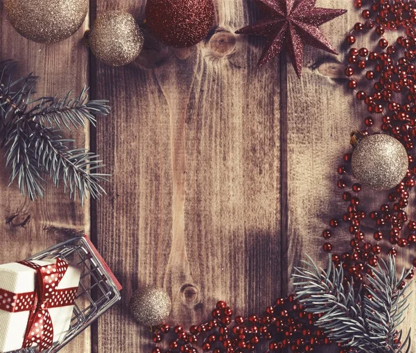 Cornice con palline di Natale, regalo e cesto della spesa su un legno — Foto Stock