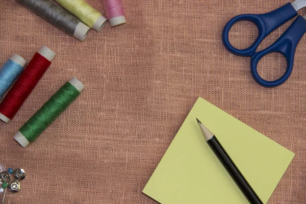 Sewing kit: multi-colored thread, thimble, scissors on a linen cloth. — Stock Photo, Image