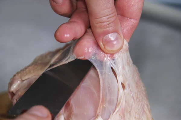 Man's hand cutting raw chicken breast. Selective focus. — Stock Photo, Image