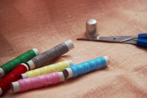 Sewing kit: multi-colored thread, thimble, scissors on a linen cloth. — Stock Photo, Image