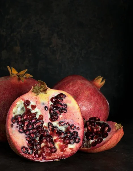 Low light image of pomegranate fruit on a dark rustic background with copy space for your text