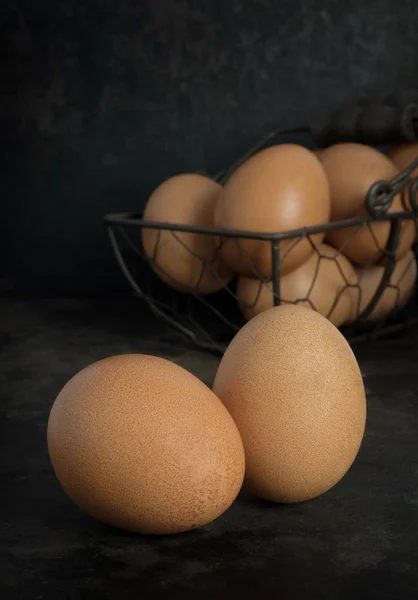 A low light image of fresh eggs in a basket on a dark background with copy space for your text