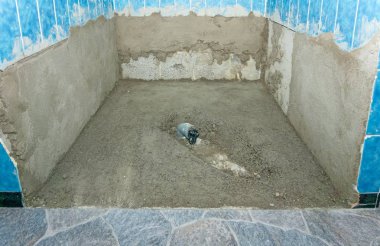 Banyo yenileme projesi sırasında yeni beton döşemeli bir duş kabini. 