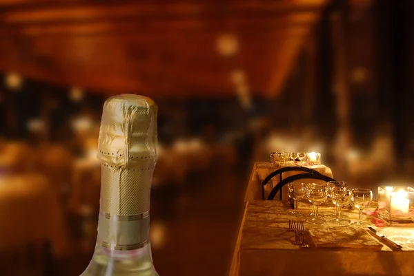 Restaurante a la luz de las velas con botella de champán en primer plano — Foto de Stock