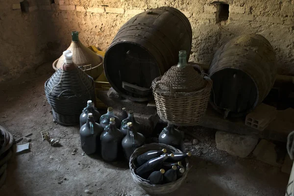 Старые demijohns в возрасте бутылки вина и деревянные бочки в подвале — стоковое фото