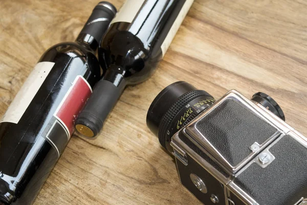 Red wine bottles and old camera — Stock Photo, Image