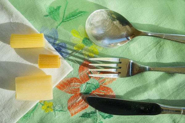 Композиція з сирими макаронами та срібними столовими приборами — стокове фото