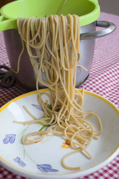 Espaguete saindo de um escorredor e um prato branco — Fotografia de Stock