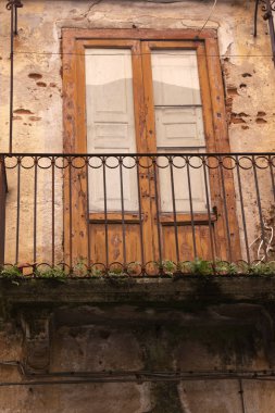 Harap olmuş ve kullanılmayan pencereleri olan terk edilmiş bir evin ön cephesi