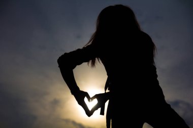 Bir kadının vücut şekli duruş eller simgesini, başka günbatımı gökyüzü üzerinde kalp şeklinde ve bulut dağ silueti