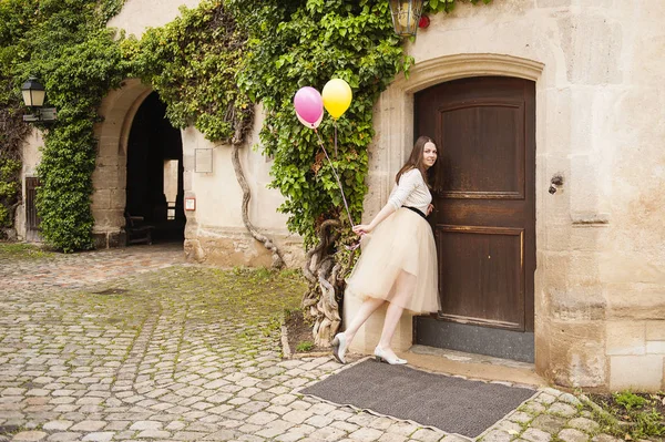 Junge Frau mit Luftballons öffnet Tür — Stockfoto