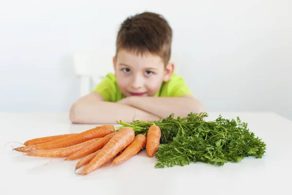 Primer plano de la zanahoria. Joven chico encantador en el fondo . —  Fotos de Stock