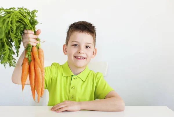 Primer plano niño encantador sostiene una zanahoria en su mano. Fondo blanco . —  Fotos de Stock