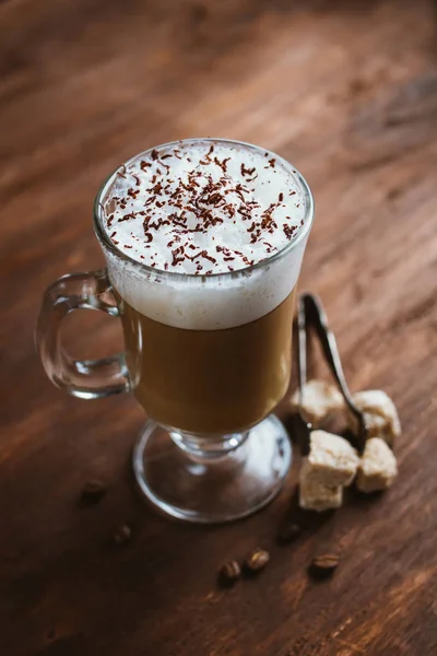 Cappuccino coffee in a glass on a brown wooden table — Stock Photo, Image