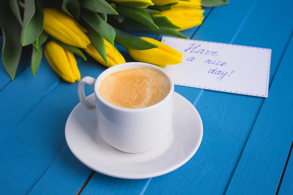 Ramo de tulipanes amarillos y una taza de café — Foto de Stock