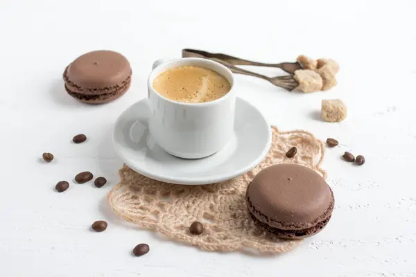 Taza de café y macarrones franceses de chocolate en una espalda de madera blanca — Foto de Stock